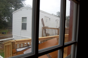 A FEMA trailer viewed from the window of a hurricane-damaged house being worked on by FCDR